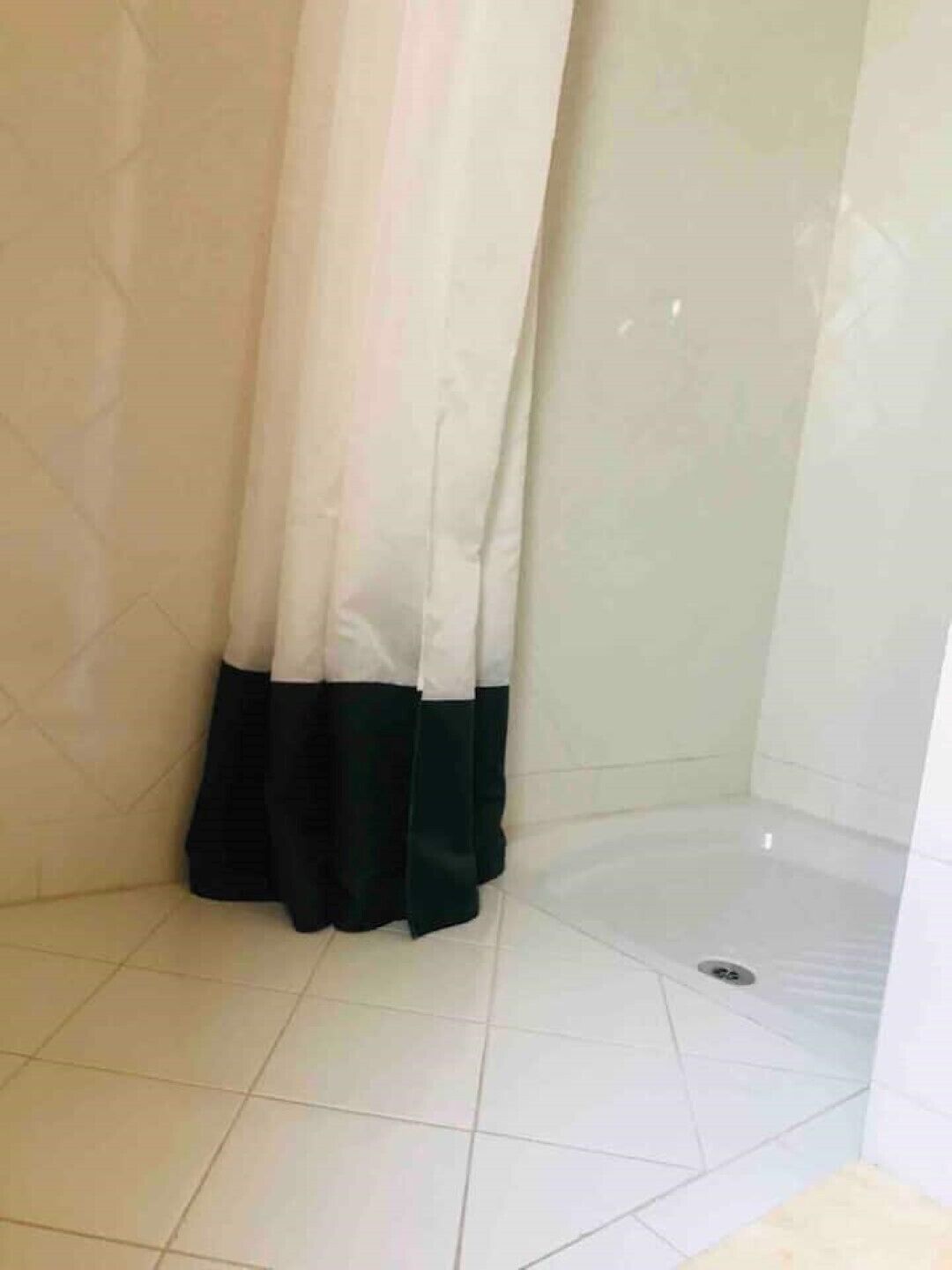 A bathroom with a shower area, tiled floor, and a curtain.