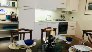 Ein Essbereich mit Tisch für vier Personen, einer Champagnerflasche und einer Küche im Hintergrund.