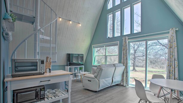 Una cocina moderna con electrodomésticos integrados, un comedor con mesa y sillas, y un amplio ventanal con vistas al exterior.