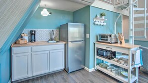 Una cocina moderna con un refrigerador de acero inoxidable, un microondas y una cafetera sobre la encimera.