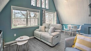 Una sala de estar acogedora con un sofá de color claro, una mesita redonda y un comedor con sillas.