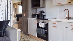 Una cocina moderna con armarios blancos, una estufa negra y una pared de acento de madera.