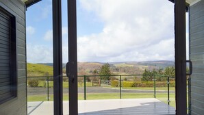 Un balcón con vistas a un paisaje rural, incluyendo colinas y una valla.