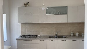 A modern kitchen with a gas stove, sink, and white cabinets. - Casa Antonia-in a strategic area to visit the main attractions of Naples (Piazza-Tralia-Pendolo)