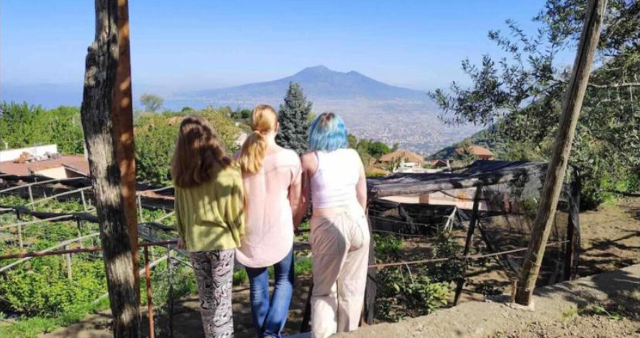 Trois personnes se tiennent près d’une clôture, d’où elles contemplent un paysage montagneux.