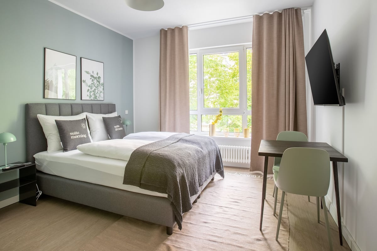 Une chambre moderne avec un lit, des tables de chevet, un bureau et un téléviseur.