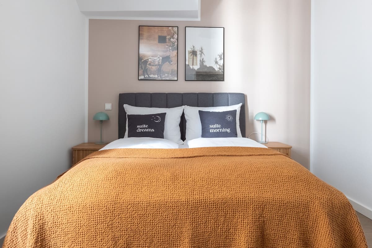 Une chambre moderne avec un grand lit, deux tables de chevet et deux lampes fixées au mur.