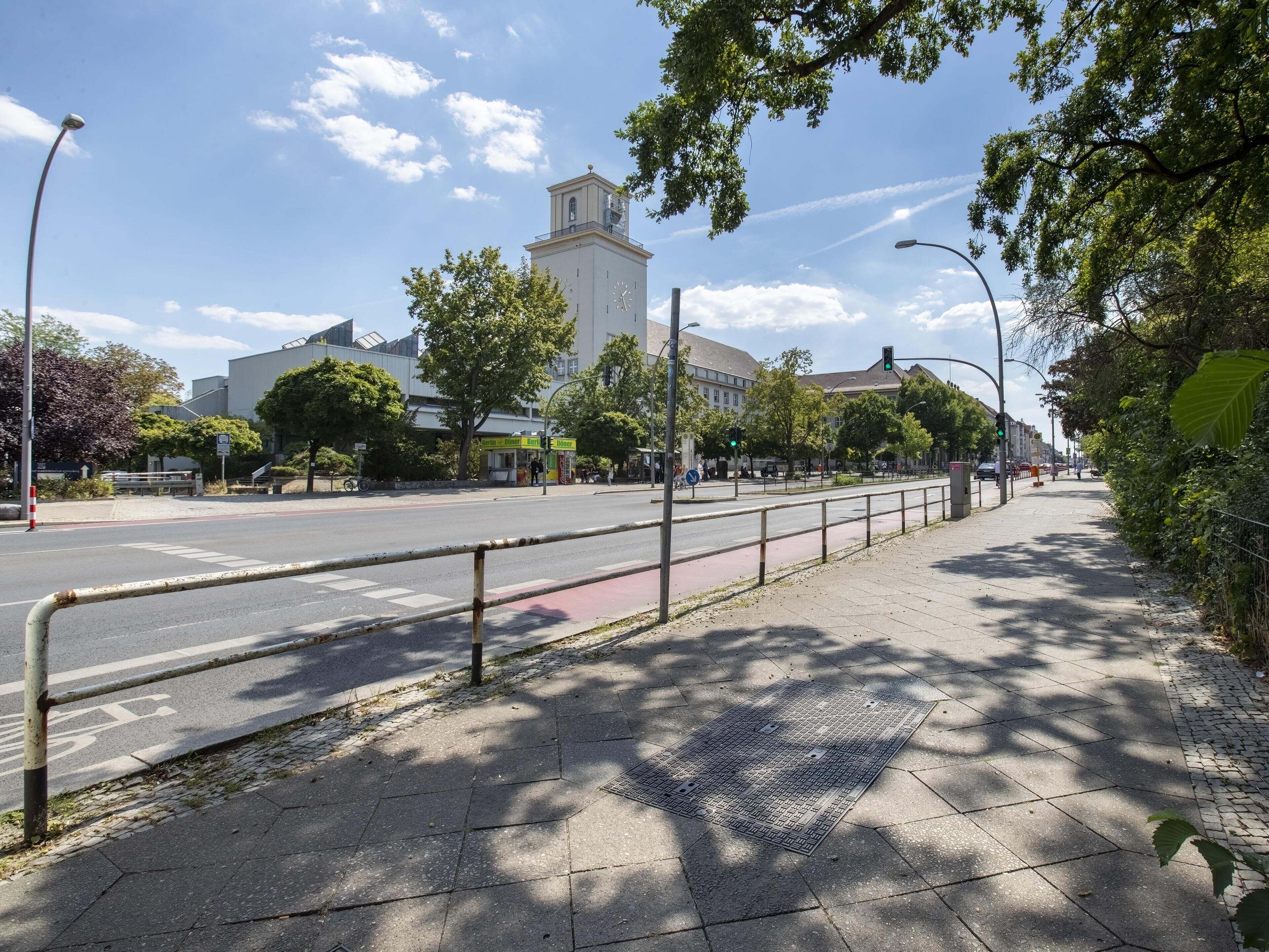 A street with a sidewalk, a pedestrian crossing, and a building with a clock tower.
