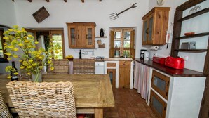 Una cocina rústica con armarios de madera, piso de espiga y un comedor con mesa y sillas de mimbre.