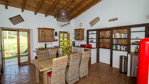 Una cocina rústica con armarios de madera, una mesa de comedor con sillas de mimbre y una estantería.