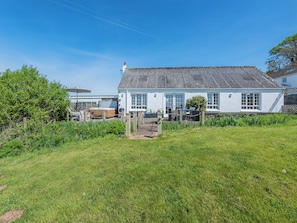 A white house with a tiled roof, a garden, and a hot tub in the yard. - 2 bedroom accommodation in Ferryside, near Carmarthen (Ferryside, near Carmarthen)