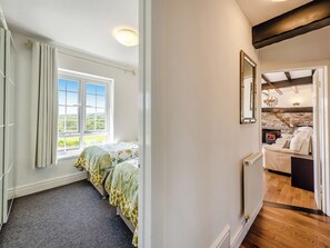 A bedroom with a large window, a bed, a radiator, and a stone fireplace. - 2 bedroom accommodation in Ferryside, near Carmarthen (Ferryside, near Carmarthen)