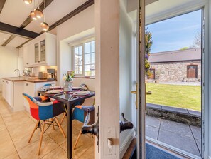 A modern kitchen with a dining area, a stone building in the background, and a view through a glass door. - 2 bedroom accommodation in Ferryside, near Carmarthen (Ferryside, near Carmarthen)