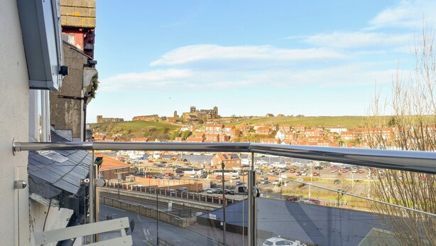 A view from a balcony overlooking a parking area with a historic building in the background.