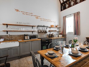 A modern kitchen with wooden shelves, a dining table set for six, and a decorative wall quote. - The Old School House 1-UK32061 (Burwarton, near Bridgnorth)