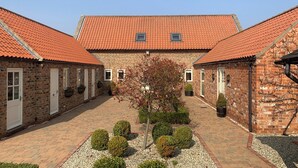 A courtyard with a central building, brick walls, and a tiled roof.