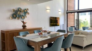 Un espace repas moderne avec une table à plateau en verre, des chaises bleues et un buffet en bois.