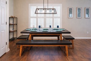 A dining area with a wooden table set for four, a bench, and a hanging light fixture. - Private Heated Pool, 10 Min to Navarre Beach (Navarre)