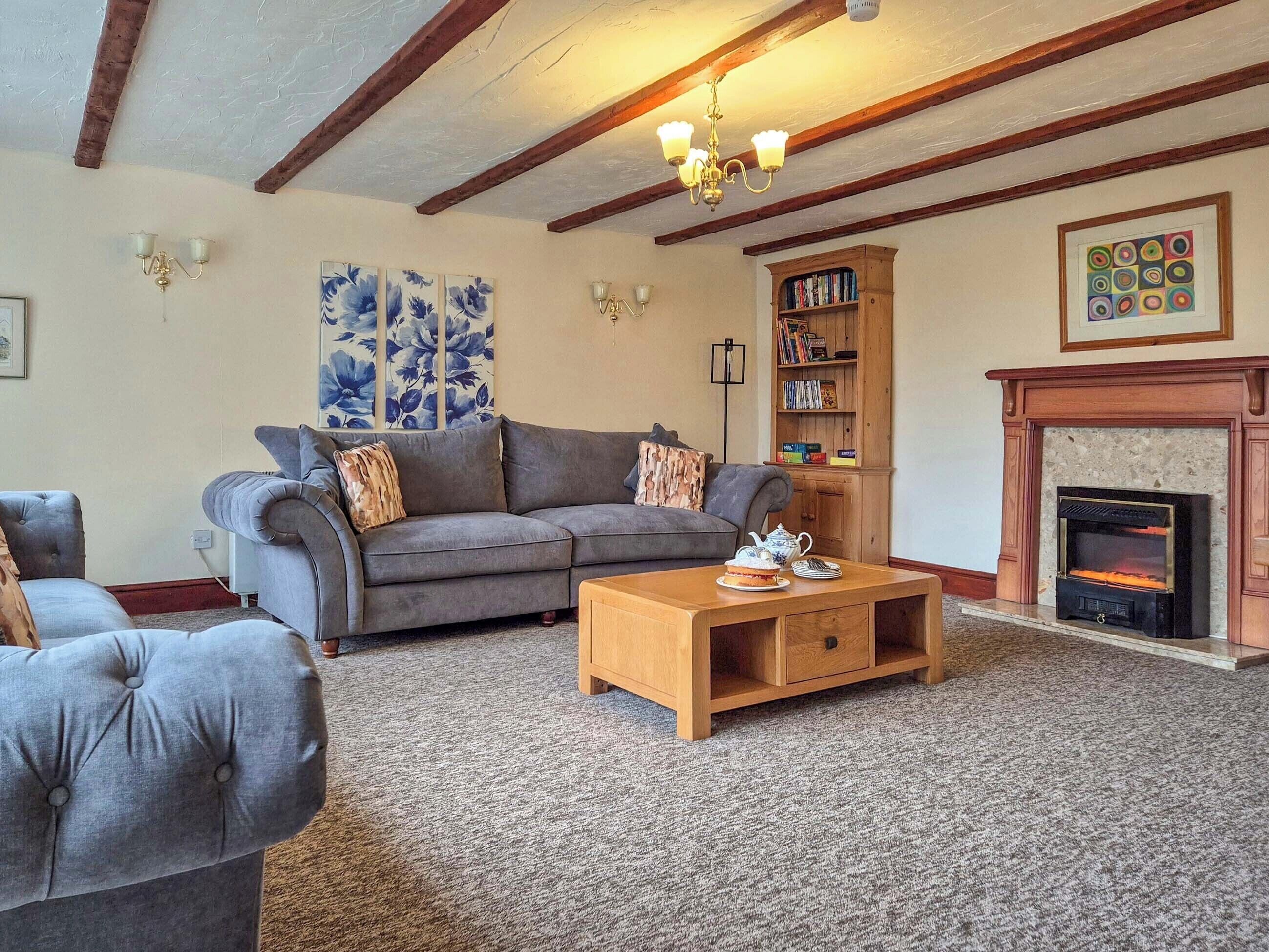 A living room with a grey sofa, a wooden coffee table, a fireplace, and a bookshelf.