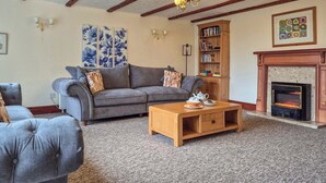 A living room with a grey sofa, a wooden coffee table, a fireplace, and a bookshelf.