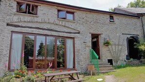 A stone building with large windows, a wooden bench, and a sign indicating a parking area.