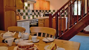 A kitchen with wooden cabinets, a microwave, a stove, and a dining table with chairs.