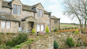 A stone house with a traditional design, featuring a stone staircase leading to a wooden deck.