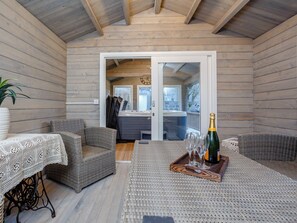 Un espace extérieur accueillant, aménagé avec des meubles en osier et une table dressée avec des verres et une bouteille de champagne.