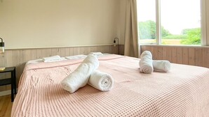 A hotel room with a large bed, a bedside table, and a window with curtains. - Idyllic house with 360 view of nature and hottub (Dalfsen)