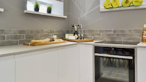 A modern kitchen with a built-in oven, a wine bottle, and a bread basket on the counter.