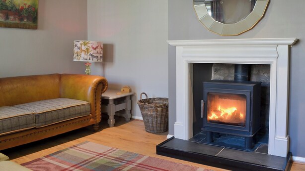 A living room with a sofa, a fireplace, a mirror, and a lamp.