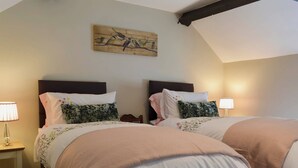 A double room with two beds, each with a headboard, bedside tables, and lamps.
