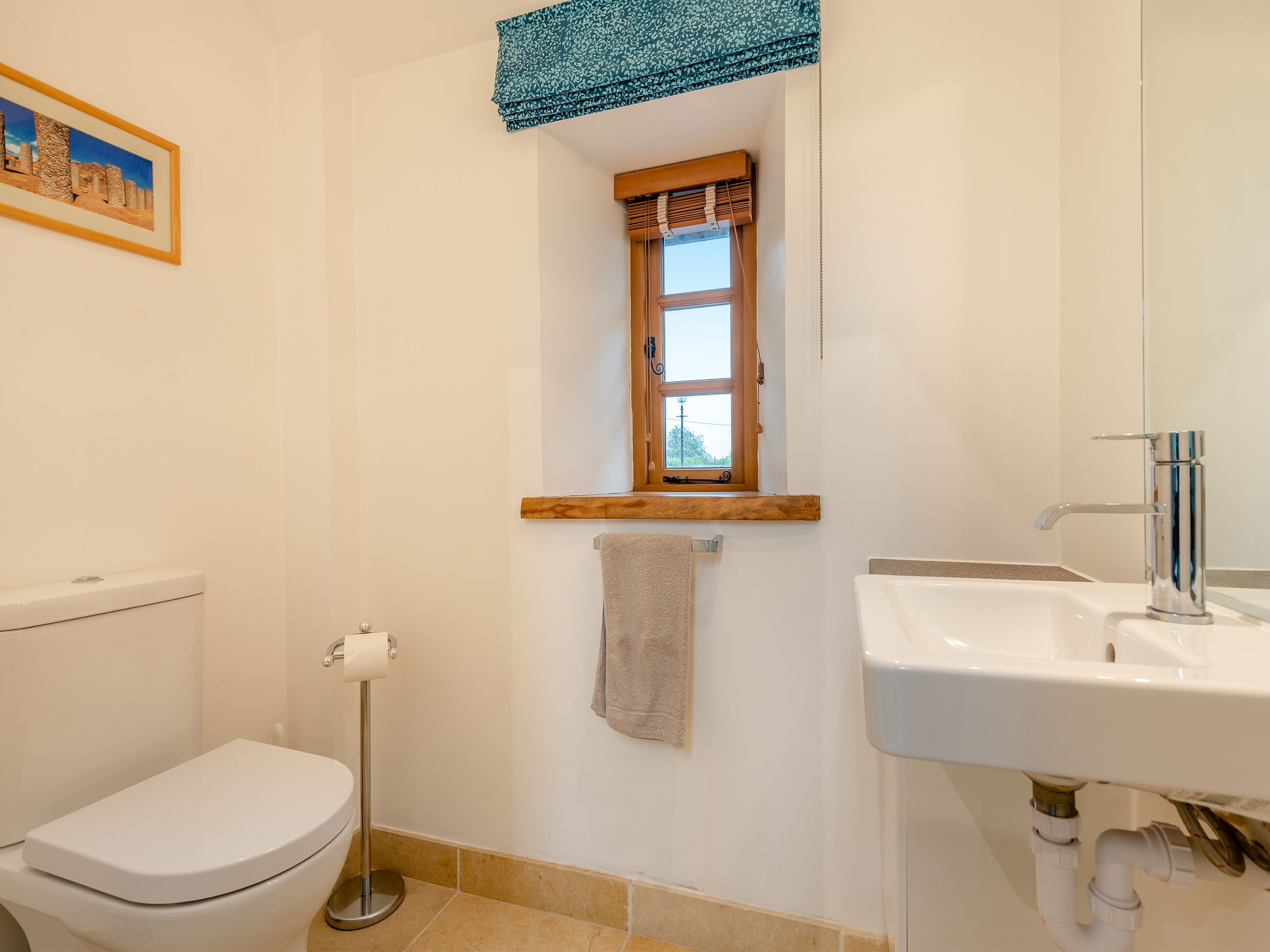 Une salle de bain équipée de toilettes, d’un lavabo et d’une fenêtre avec un cadre en bois.