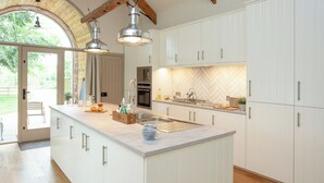 Et moderne køkken med hvide skabe, en stor ø, rustfrie stålapparater og en backsplash med fiskebensmønster.