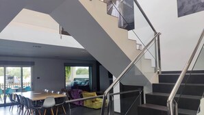 A modern interior with a staircase, a dining area, and a view through large windows. - CASA DEL SOL, LUXURY AND RELAX BY THE SEA (Peñíscola)