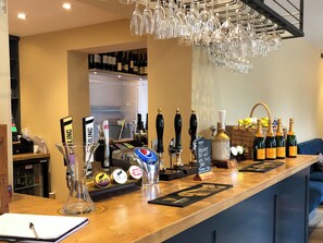 Un espace bar doté de plusieurs robinets, d’une carafe en verre et d’un panier rempli de bouteilles de champagne.