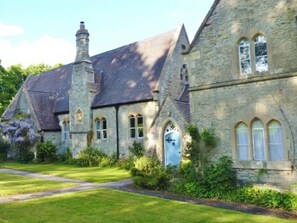 A stone building with a steeply pitched roof, arched windows, and a central chimney. - The Old Kitchen -UK32062 (Burwarton, near Bridgnorth)