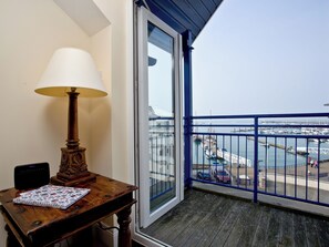 Een balkon met uitzicht op een jachthaven, een tafel met een lamp en een notitieboek.