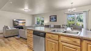 A modern kitchen with a dishwasher, granite countertop, and wooden cabinets. - Willow Park House on Fairway Ln (Logan)