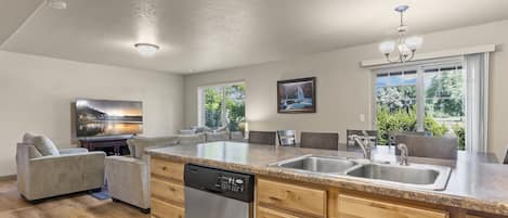 A modern kitchen with a dishwasher, granite countertop, and wooden cabinets.