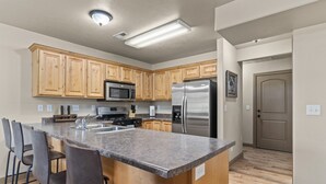 A modern kitchen with wooden cabinets, stainless steel appliances, and a granite countertop. - Willow Park House on Fairway Ln (Logan)