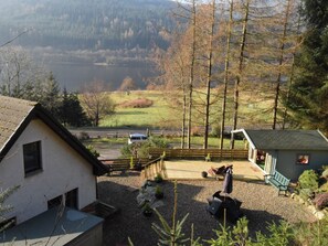 A house with a patio, a small shed, and a view of a lake and forest.