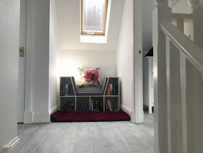A room with a bookshelf, a red rug, and a window with a view.