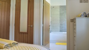 Una camera da letto con un letto, un armadio, uno specchio e un bagno dotato di vasca e doccia.