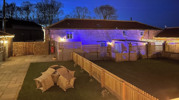 Una casa in mattoni con un cortile recintato, un piccolo portico e una staccionata di legno.