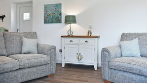 Un soggiorno con due divani decorati, un mobile bianco con maniglia a forma di cuore e un quadro floreale appeso al muro.