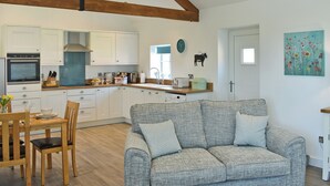 Un'ampia cucina con travi in legno, mobili bianchi e una zona pranzo con tavolo e sedie in legno.