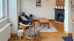 Un salon chaleureux avec un canapé bleu, une chaise en bois, une petite table et une cheminée.