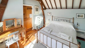 Une chambre à coucher avec un lit en bois, un bureau avec une chaise, une commode et un miroir.