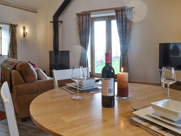 A cozy living room with a fireplace, a dining table set with wine glasses, a candle, and a bottle of wine.